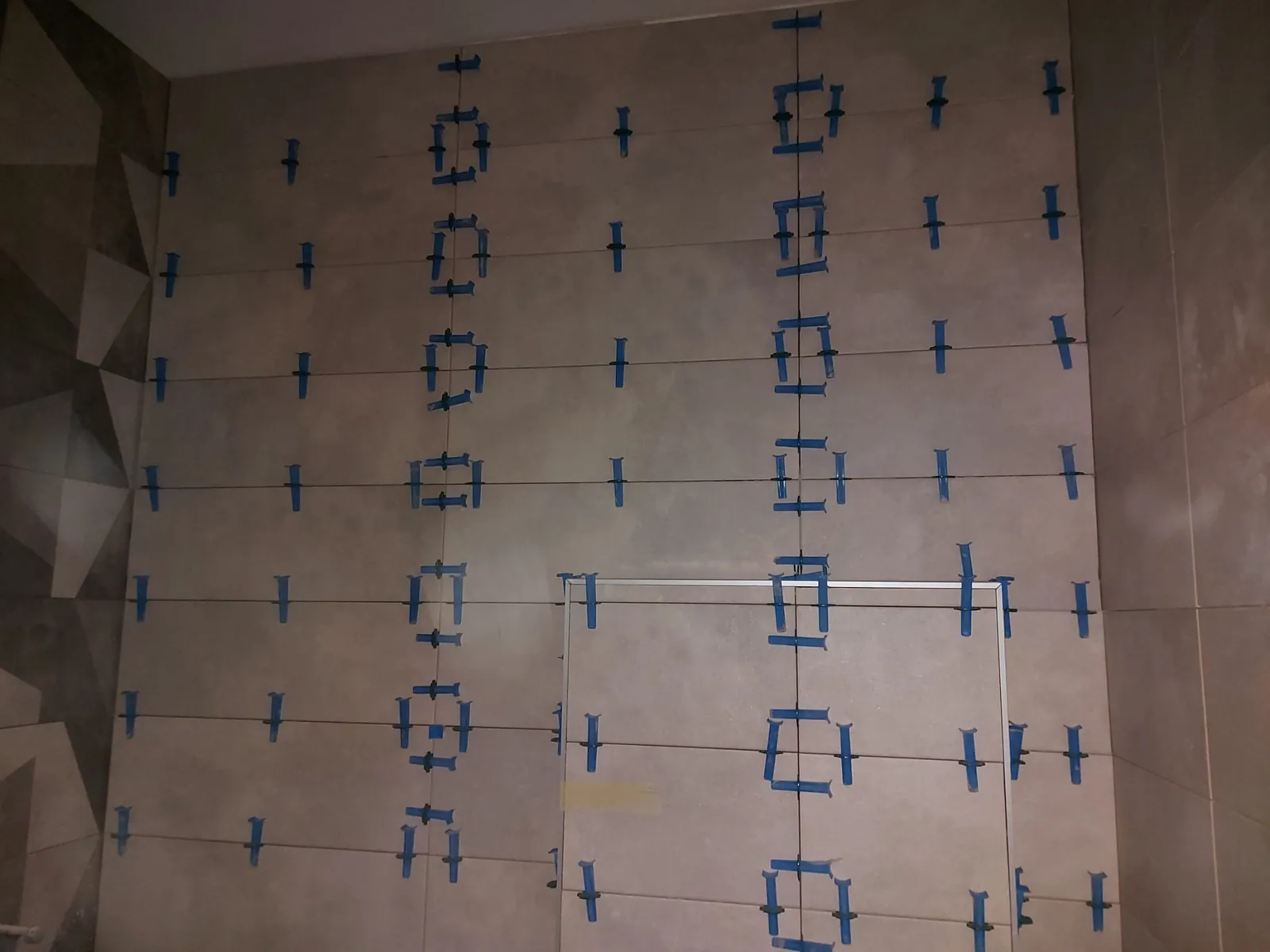 Falburkolás szintezőrendszerrel, geometriai dekorcsempe mellett
