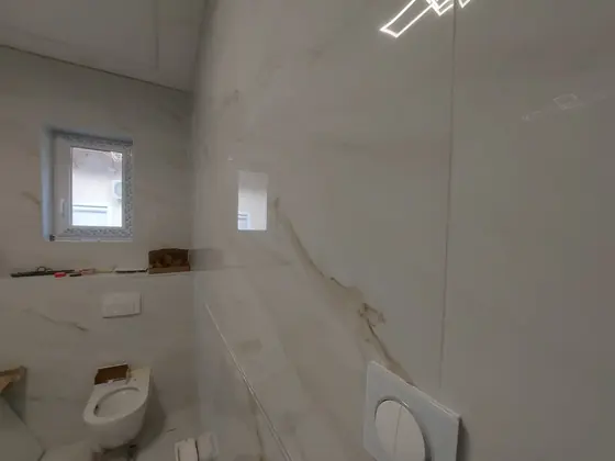 Márványhatású burkolat fürdőszobában, mosdóval és WC-vel