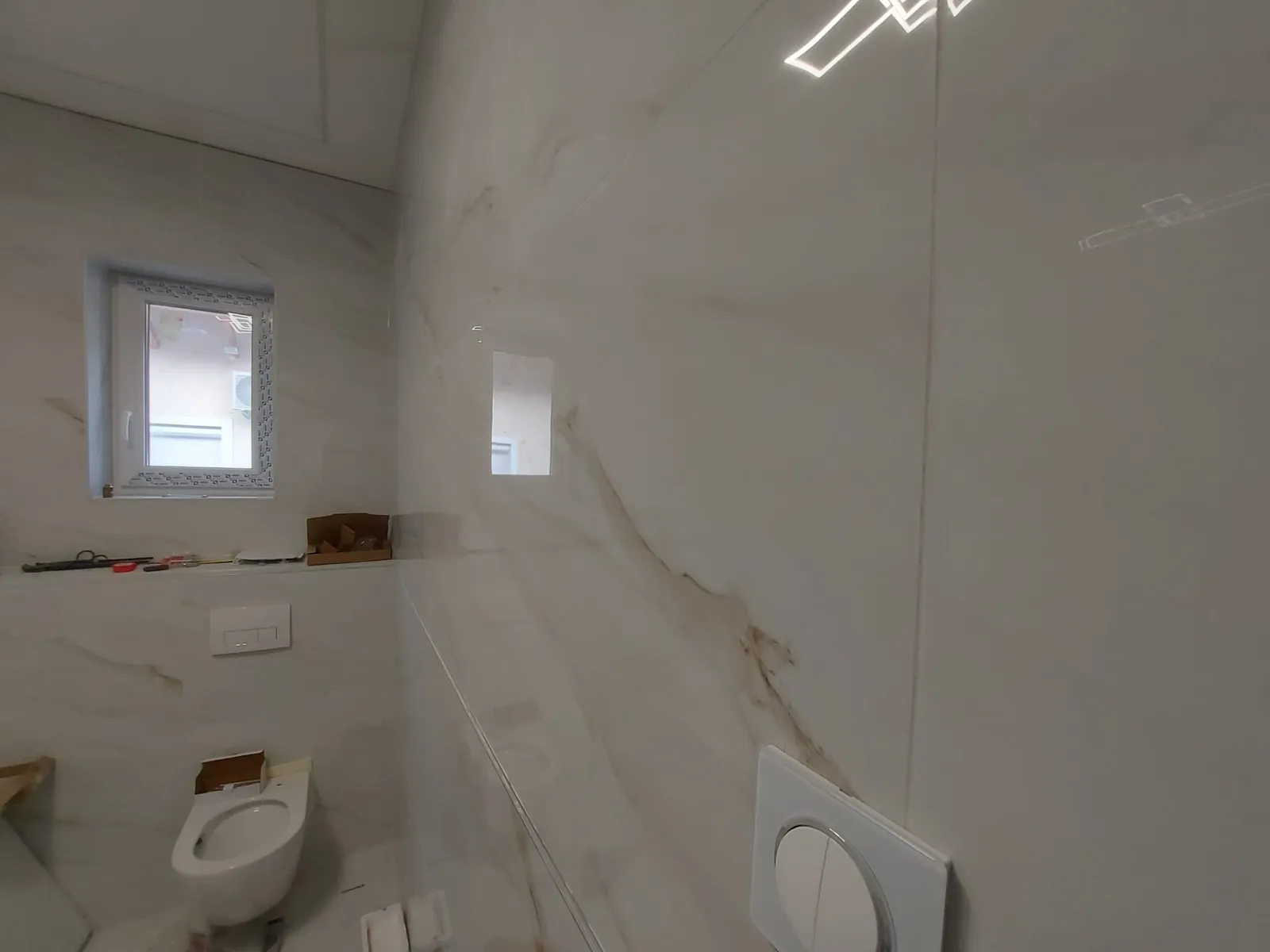 Márványhatású burkolat fürdőszobában, mosdóval és WC-vel